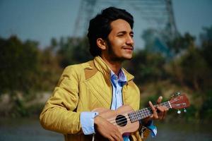 Young handsome indian man plays ukulele photo