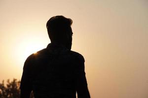 Silhouette of man watching sunset over the sea. Male silhouette and sea sunset. photo