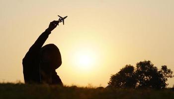 Happy young boy with a toy airplane on a sunset background over a wheat field photo