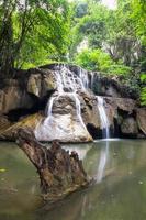 Waterfall cliff with log in rainforest photo