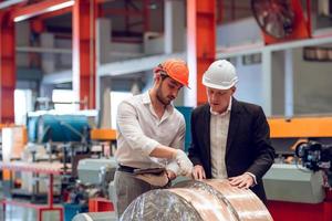 Factory worker foreman and engineer manager working together at industrial worksite , wearing hard hat for safety photo