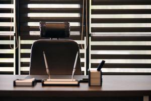 Business office workplace. Work place for chief, boss or other employees. Table and comfortable chair. Light through the half open blinds photo