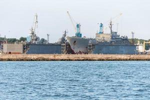 grandes barcos de la armada de hierro en el astillero para su reparación. gran grúa en el astillero. puerto de mar azul foto