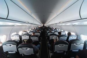 Airplane cabin seats with passengers. Economy class of new cheapest low-cost airlines without delay or cancellation of flight. Travel trip to another country. photo