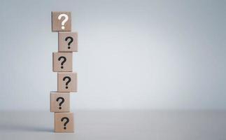 Hand hold Wooden cube block in question mark mean what on cement table background, column of wooden blocks with question sign mark. copy space,FAQ frequently asked questions, Answer, Information photo