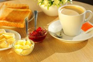 pan tostado, mantequilla y taza de café para el desayuno foto