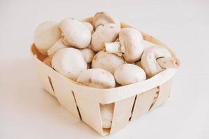 Champignon mushrooms in a wicker basket on a white background photo