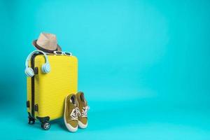 Yellow suitcase with sun glasses, hat and camera on pastel blue background. travel concept. minimal style photo