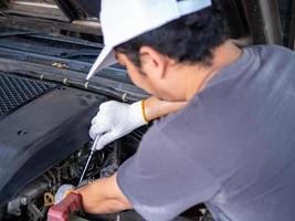 mecánico sosteniendo un mango de llave de bloque mientras arregla un automóvil. foto