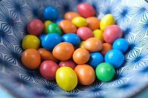 child boy picking multi-colored sweet candies in a bowl close up photo