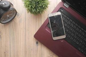 Top view of broken smart phone on a laptop on table photo