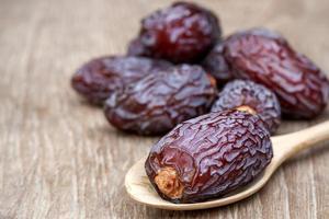 Close-up Medjool dates or dates fruit in wooden spoon on table, This fruit is highly nutritious and is commonly eaten during fasting or Ramadan. photo