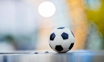 The soccer ball is placed on a wooden floor and has a blurred background with beautiful bokeh. photo
