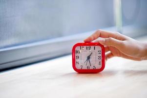 Hand and red alarm clock that shows the alarm at all Every morning, the concept of punctuality photo