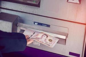 presione dinero en el cajero automático del banco. concepto de negocio financiero con espacio de copia foto
