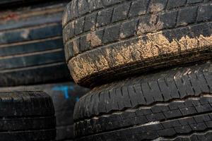 Stack of old tires. Pile of used tires. Black rubber tire of car. Dirty used tyres. Closeup old tyres waste for recycle. Closeup tread of an old dirty tyre. Change car tire for safety concept. photo