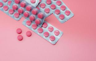 Top view pink tablet pills and blister pack of pills on pink background. Prescription drug. Vitamins, minerals, and supplements. Pharmaceutical industry. Health care and medicine. Pharmacy product. photo