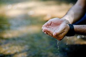 Hands and water flowing from natural waterfalls Water concept from natural waterfall photo