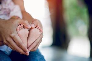 Newborn baby's feet and father's hands holding their feet with love and concern for their children. photo