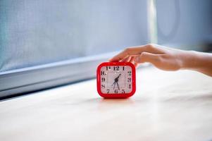 Hand and red alarm clock that shows the alarm at all Every morning, the concept of punctuality photo