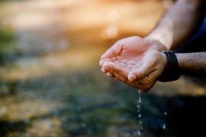 Hands and water flowing from natural waterfalls Water concept from natural waterfall photo