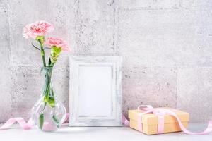 primer plano, espacio de copia, maqueta, hermoso concepto de evento del día de la madre fotografía de decoración de caja de regalo hecha a mano, claveles frescos en flor con cinta de color rosa aislada en papel tapiz gris foto