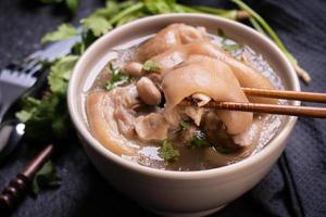 Top view, close up, copy space, Taiwan asian distinctive street food, peanut pork knuckle soup in a beige ivory creamy-white colored bowl isolated on dark shale slate table photo