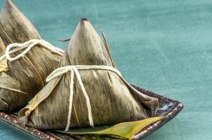 Close up, copy space, famous chinese food in dragon boat duan wu festival, steamed rice dumplings pyramidal shaped wrapped by bamboo leaves made by sticky rice raw ingredients photo