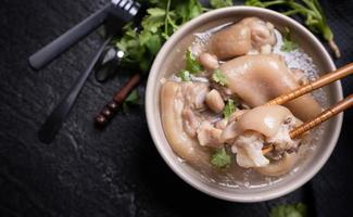 Top view, close up, copy space, Taiwan asian distinctive street food, peanut pork knuckle soup in a beige ivory creamy-white colored bowl isolated on dark shale slate table photo