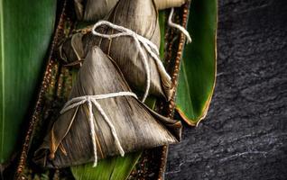 Close up, copy space, top view, famous asian chinese tasty handmade food in dragon boat duan wu festival, steamed rice dumplings shaped pyramidal by leaves ingredients photo