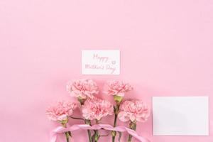 Top view, flay lay, copy space, close up, mock up, mothers day thanks design concept. Beautiful fresh blooming baby pink color carnations isolated on bright pink background photo