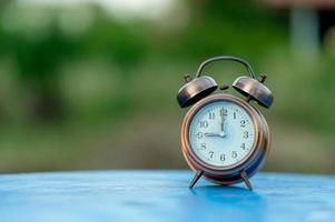 Golden alarm clock picture placed on a blue table, green background Punctual concept With copy space photo