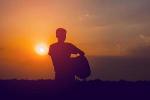 The silhouette of a guitarist who holds a guitar and has a sunset, silhouette concept. photo