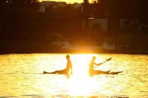 young couple paddling in the sundown photo