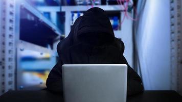 Hacker using computer with digital interface while sitting at desk of blurry interior. Hacking and thief concept. photo