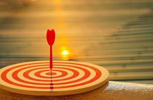 Close-up red dart arrow hitting in target center of dartboard   Business goal or success goal marketing Strategy and business competition concept photo