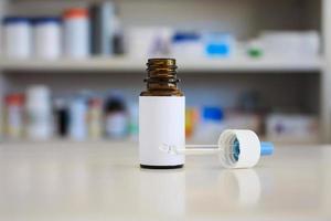 Medical Glass Brown Bottle With White Label, nasal drop medicine with blur drugstore shelves background photo