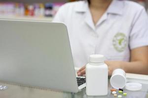 farmacéutico con computadora portátil y medicamentos en la farmacia foto