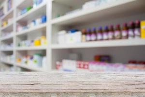 mostrador de madera con estantes borrosos de medicamentos en la farmacia foto