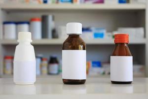 etiqueta blanca en blanco del frasco de medicina con estantes borrosos de medicamento en el fondo de la farmacia foto