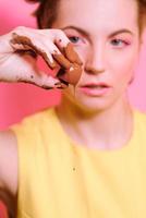 portrait of cute attractive blonde young woman with chocolate candy in her fingers