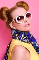 Portrait of cute attractive blonde young woman in sunglasses and blue neckerchief on pink background photo