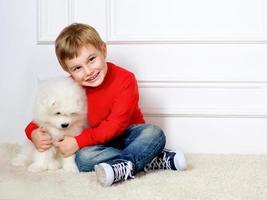 smiling little boy three years old playing with white puppies of Samoyed in studio
