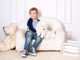 smiling little boy three years old playing with white puppies of Samoyed in studio photo