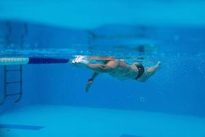 deportista caucásico nadando en la piscina bajo el agua foto