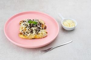 Pisang panggang, Grilled banana topped with chocolate sprinkles, grated cheese, and sweet white milk. Served on plate with mint leaves on grey background. photo
