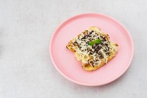 Pisang panggang, Grilled banana topped with chocolate sprinkles, grated cheese, and sweet white milk. Served on plate with mint leaves on grey background. photo