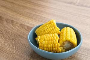 Jagung manis rebus or boiled sweet corn slices served on bowl on wooden background. Space for text. photo