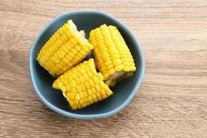 Jagung manis rebus or boiled sweet corn slices served on bowl on wooden background. Space for text. photo