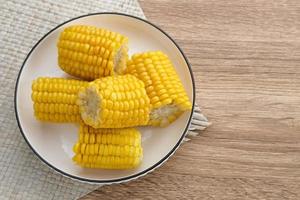 Jagung manis rebus or boiled sweet corn slices served on bowl on wooden background. Space for text. photo